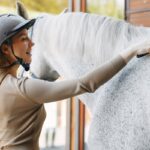 Il grooming del cavallo: la pulizia quotidiana come controllo sanitario ed estetico Beautiful woman standing with a horse